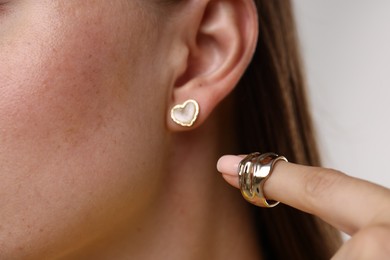Photo of Woman wearing stylish earring and ring on light background, closeup