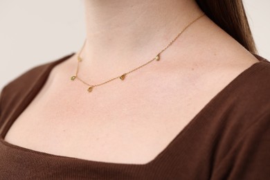 Photo of Woman wearing stylish necklace on light grey background, closeup