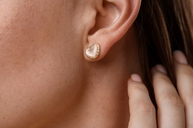 Photo of Woman wearing stylish heart-shaped earring, closeup view