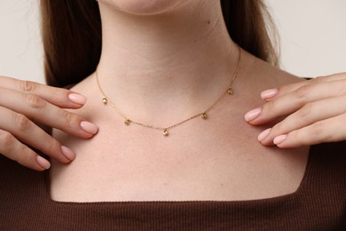 Photo of Woman wearing stylish necklace on light grey background, closeup