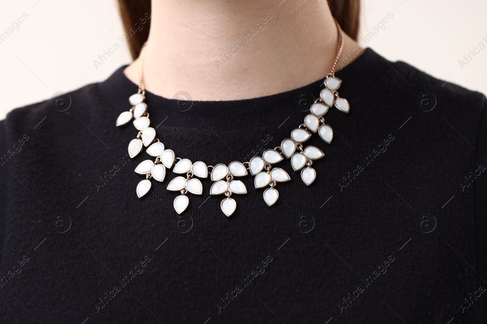Photo of Woman wearing stylish necklace on light background, closeup