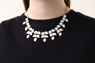 Photo of Woman wearing stylish necklace on light background, closeup