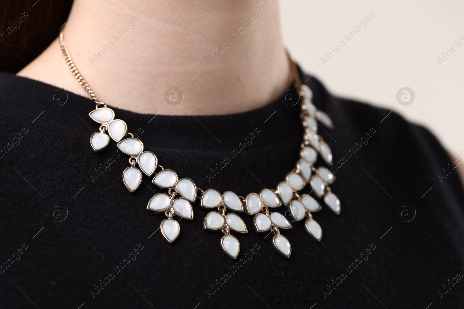 Photo of Woman wearing stylish necklace on light background, closeup