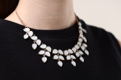 Photo of Woman wearing stylish necklace on light background, closeup