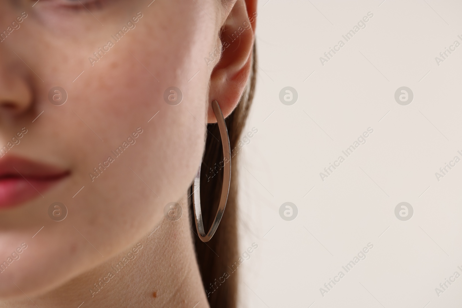 Photo of Woman wearing stylish earring on light grey background, closeup. Space for text