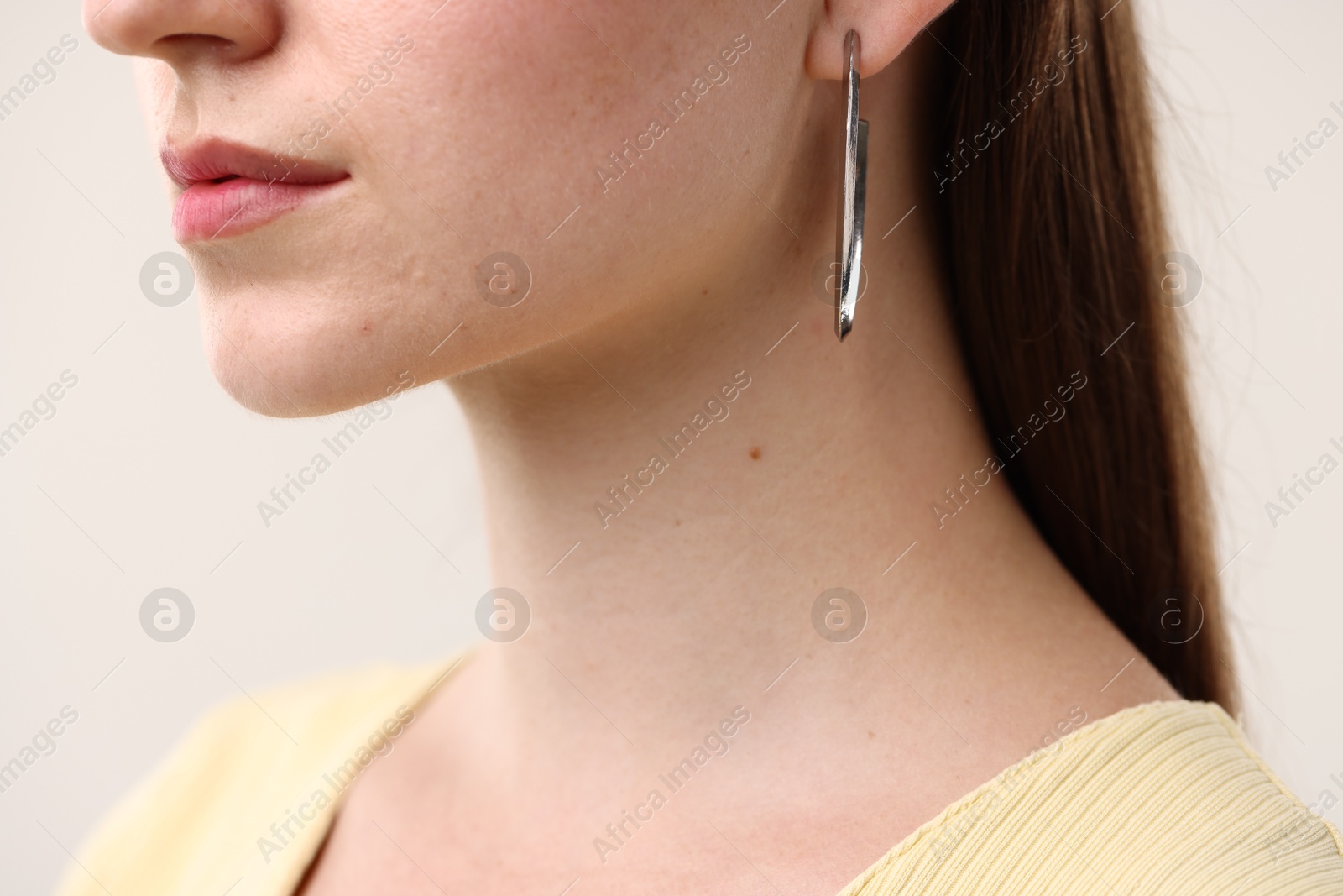 Photo of Woman wearing stylish earring on light grey background, closeup