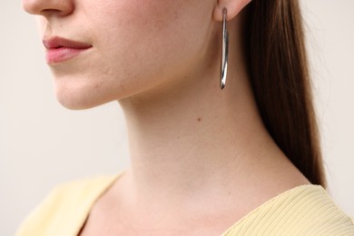 Photo of Woman wearing stylish earring on light grey background, closeup