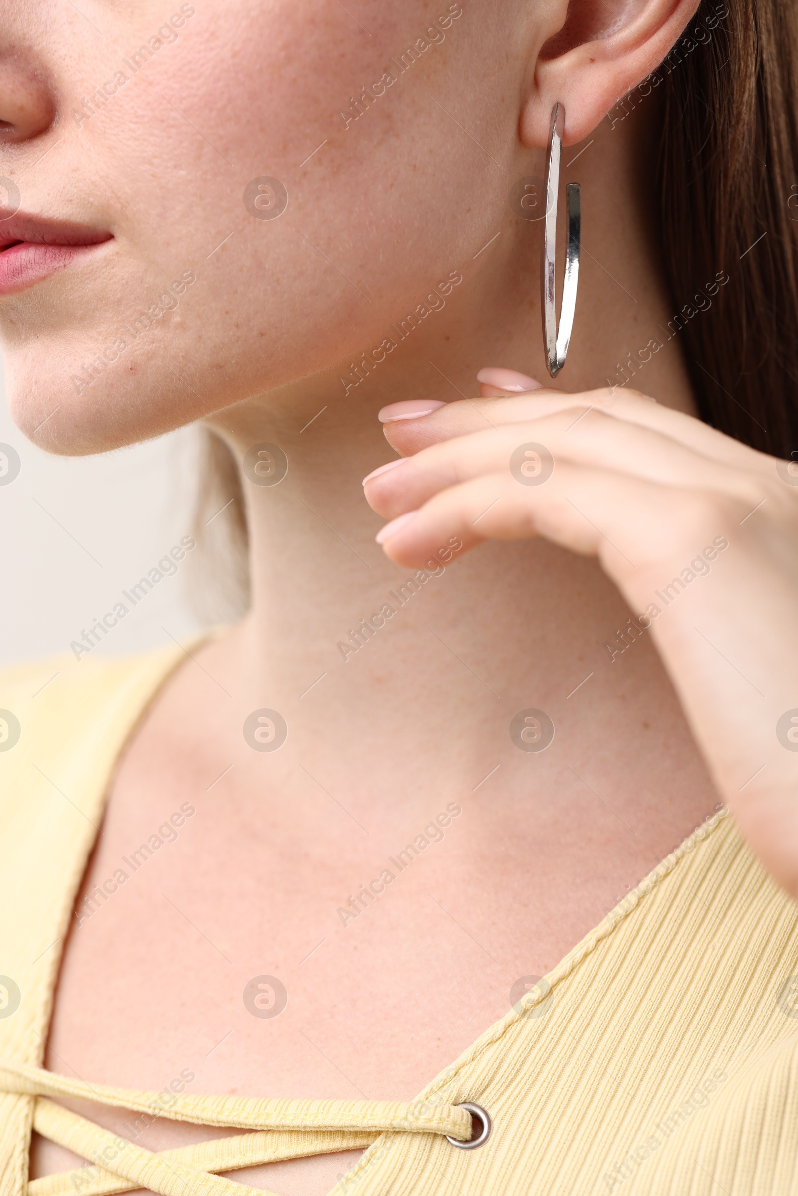 Photo of Woman wearing stylish earring on grey background, closeup