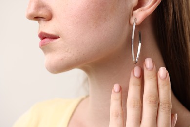 Photo of Woman wearing stylish earring on grey background, closeup