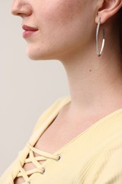 Photo of Woman wearing stylish earring on grey background, closeup