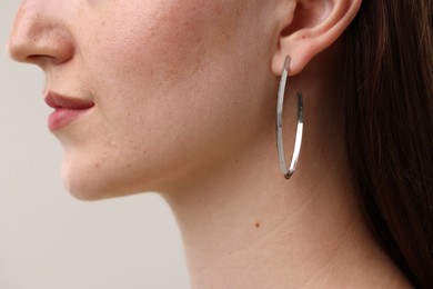 Photo of Woman wearing stylish earring on grey background, closeup