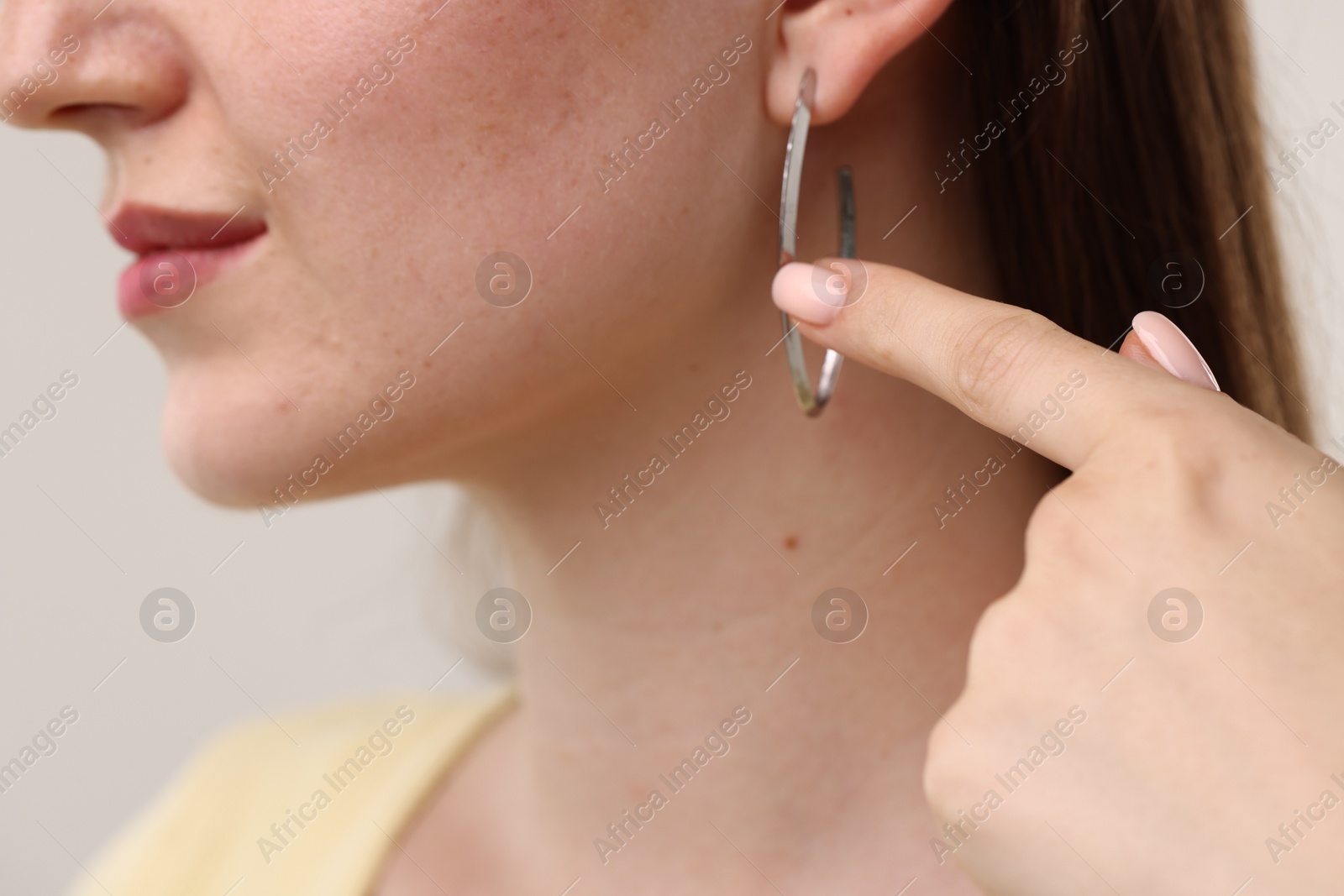 Photo of Woman pointing at her stylish earring on grey background, closeup