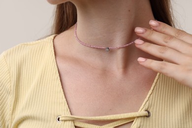 Photo of Woman wearing stylish necklace on light grey background, closeup
