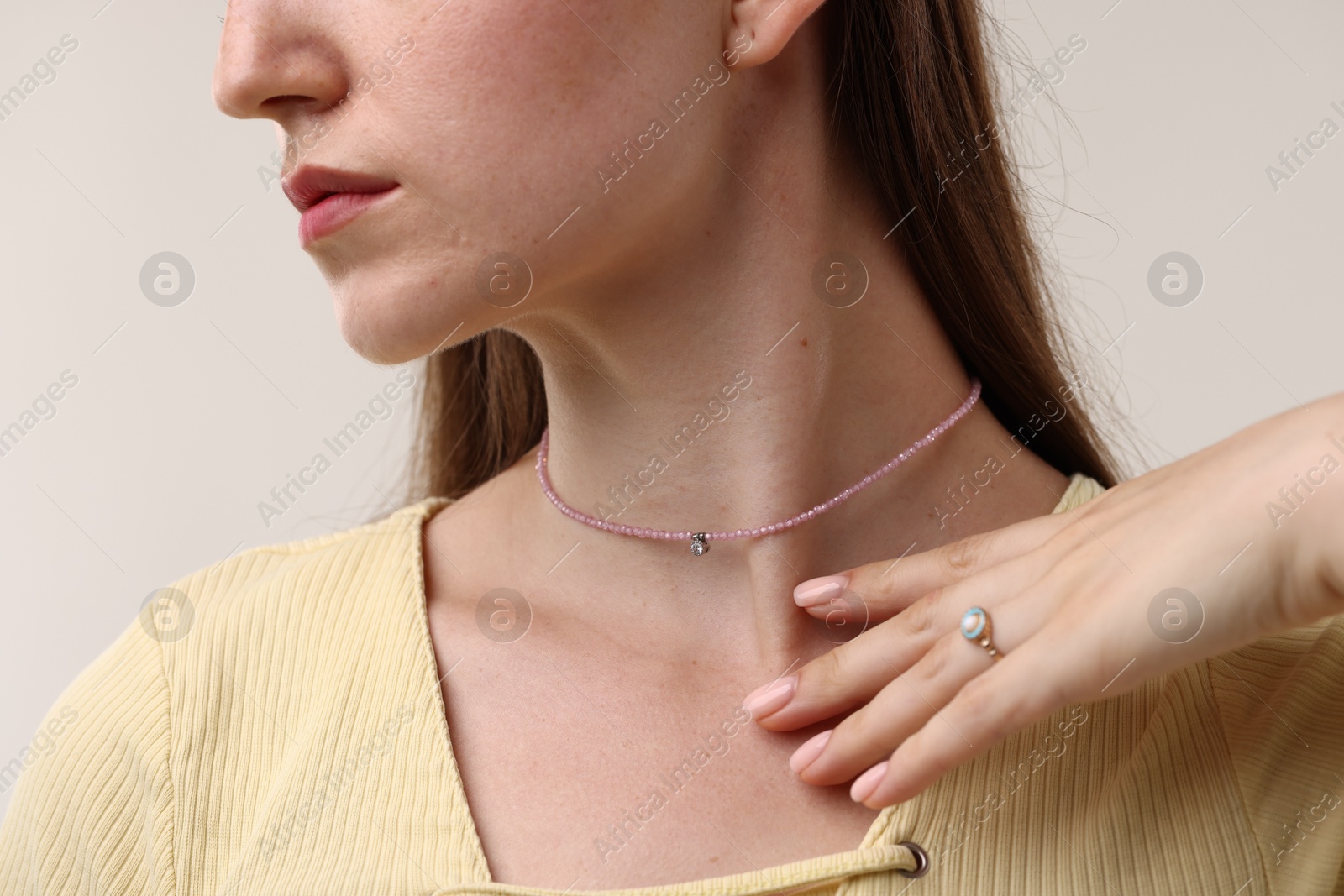 Photo of Woman wearing stylish necklace on light grey background, closeup