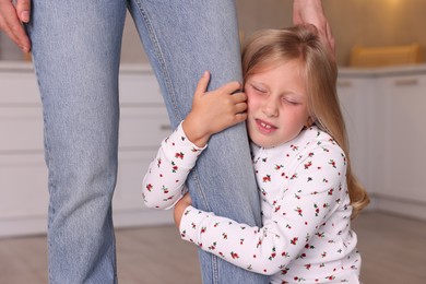 Photo of Little girl afraid to leave without mother and hugging her at home. Separation anxiety