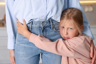 Photo of Little girl afraid to leave without mother and hugging her at home. Separation anxiety