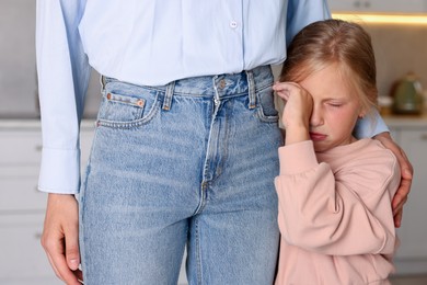 Photo of Little girl afraid to leave without mother and clinging to her at home. Separation anxiety