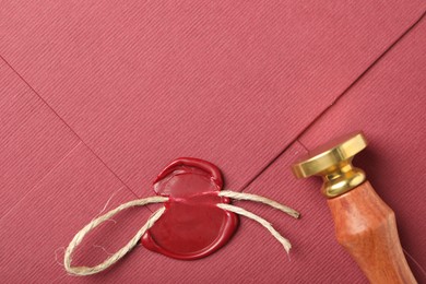 Photo of Beautiful envelope with red wax seal, twine and stamp, top view