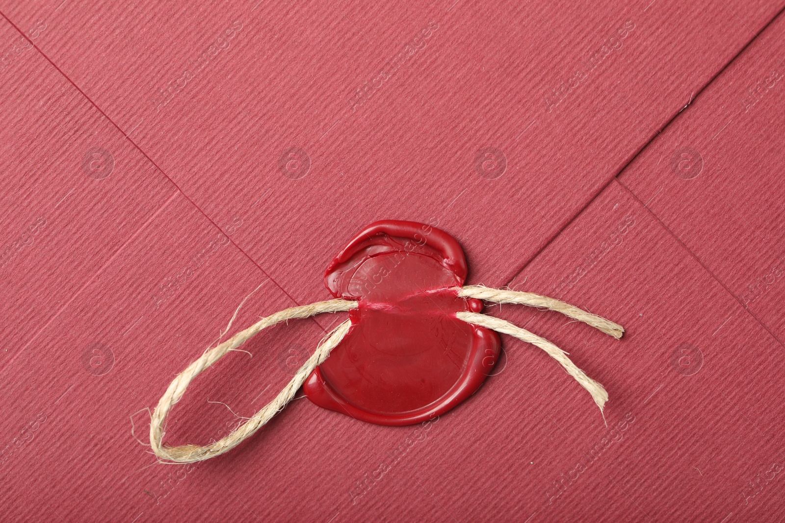 Beautiful envelope with red wax seal and twin as background, top view Photo of Beautiful envelope with red wax seal and twin as background, top view