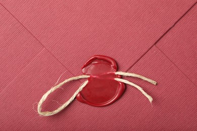 Photo of Beautiful envelope with red wax seal and twin as background, top view
