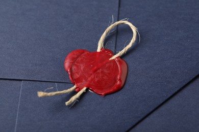 Photo of Beautiful envelope with red wax seal and twin as background, closeup