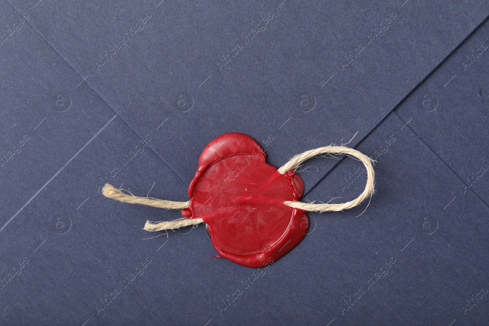 Beautiful envelope with red wax seal and twin as background, top view Photo of Beautiful envelope with red wax seal and twin as background, top view