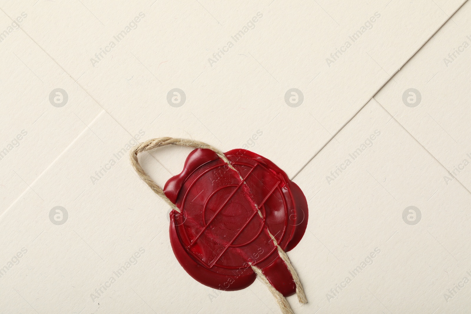 Beautiful envelope with red wax seal and twin as background, top view Photo of Beautiful envelope with red wax seal and twin as background, top view
