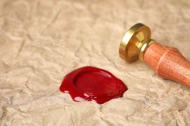 Photo of Beautiful wax stamp and red seal on crumpled paper, closeup