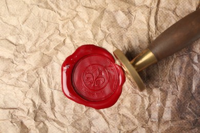 Photo of Beautiful wax stamp and red seal on crumpled paper, top view