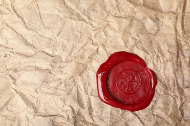 Photo of Red wax seal on crumpled paper, top view. Space for text
