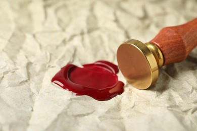 Photo of Beautiful wax stamp and red seal on crumpled paper, closeup