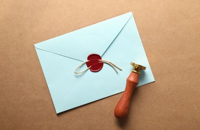 Photo of Beautiful wax stamp, envelope with red seal and twine on beige background, top view