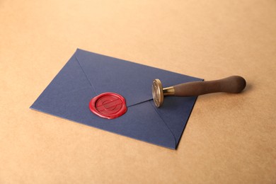 Photo of Beautiful wax stamp, envelope with red seal and twine on beige background, closeup