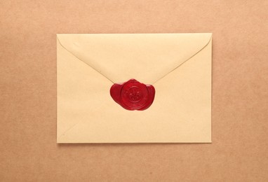 Photo of Beautiful envelope with red wax seal on beige background, top view