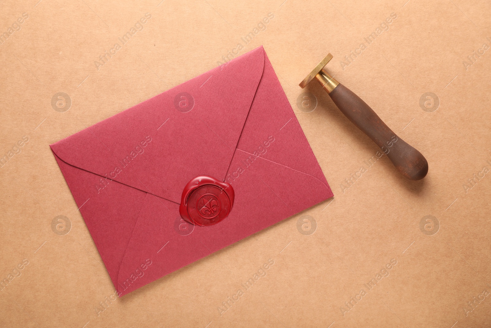 Beautiful wax stamp and envelope with seal on beige background, flat lay Photo of Beautiful wax stamp and envelope with seal on beige background, flat lay