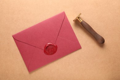 Photo of Beautiful wax stamp and envelope with seal on beige background, flat lay