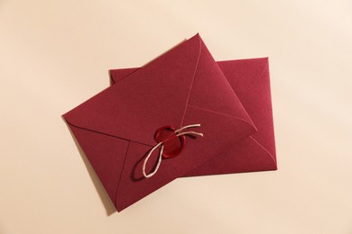 Photo of Beautiful envelopes with wax seal and twine on beige background, top view