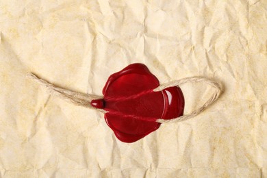 Photo of Red wax seal with twine on crumpled paper, top view