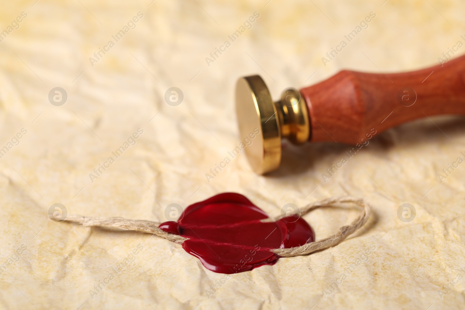 Beautiful wax stamp and red seal with twine on crumpled paper, closeup Photo of Beautiful wax stamp and red seal with twine on crumpled paper, closeup