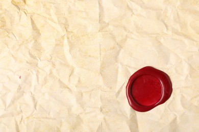 Photo of Red wax seal on crumpled paper, top view. Space for text