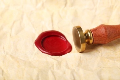 Photo of Beautiful wax stamp and red seal on crumpled paper, closeup