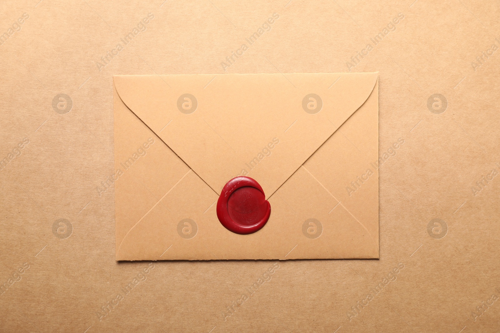 Beautiful envelope with red wax seal on beige background, top view Photo of Beautiful envelope with red wax seal on beige background, top view