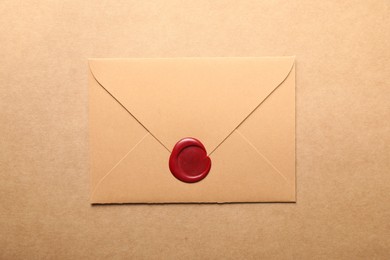 Photo of Beautiful envelope with red wax seal on beige background, top view