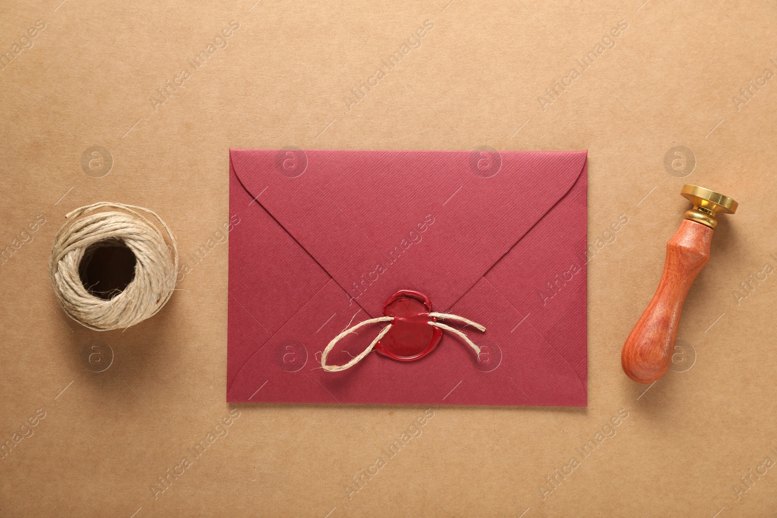 Beautiful wax stamp, twine and envelope with seal on beige background, flat lay Photo of Beautiful wax stamp, twine and envelope with seal on beige background, flat lay