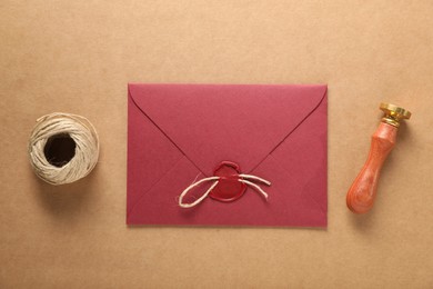 Photo of Beautiful wax stamp, twine and envelope with seal on beige background, flat lay