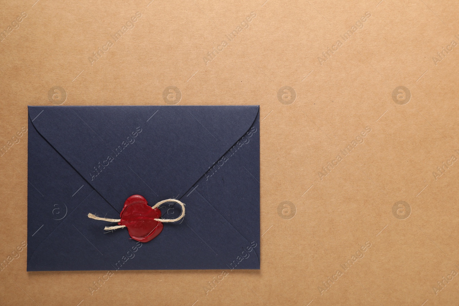 Beautiful envelope with red wax seal and twine on beige background, top view. Space for text Photo of Beautiful envelope with red wax seal and twine on beige background, top view. Space for text