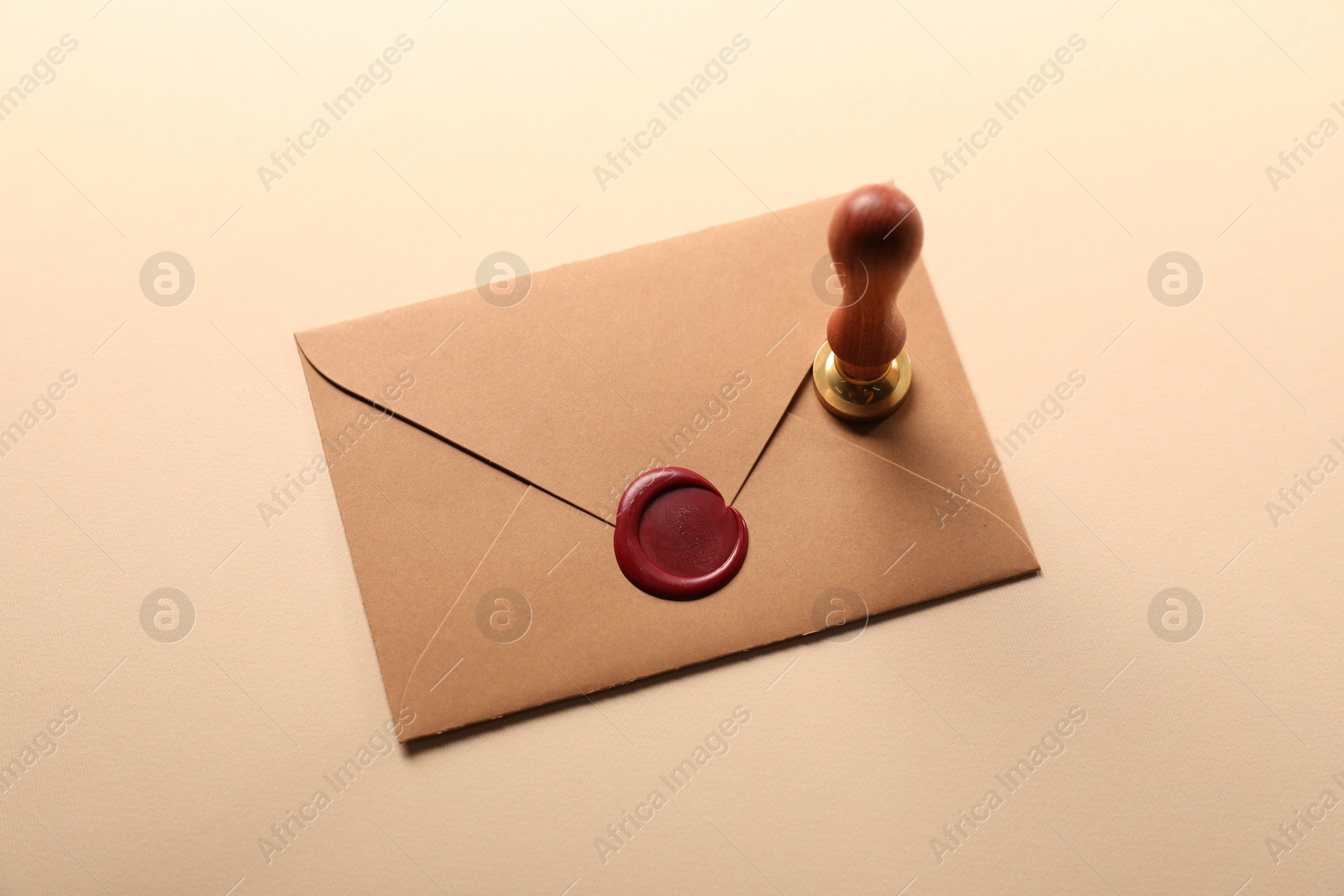 Beautiful wax stamp and envelope with seal on beige background, above view Photo of Beautiful wax stamp and envelope with seal on beige background, above view