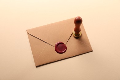Photo of Beautiful wax stamp and envelope with seal on beige background, above view