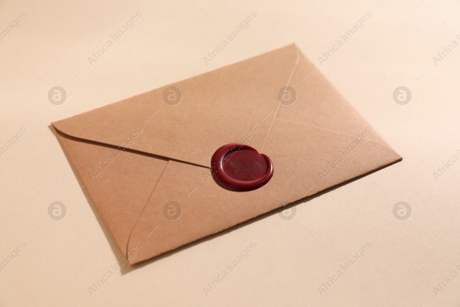 Beautiful envelope with red wax seal on beige background, closeup Photo of Beautiful envelope with red wax seal on beige background, closeup