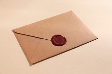 Photo of Beautiful envelope with red wax seal on beige background, closeup